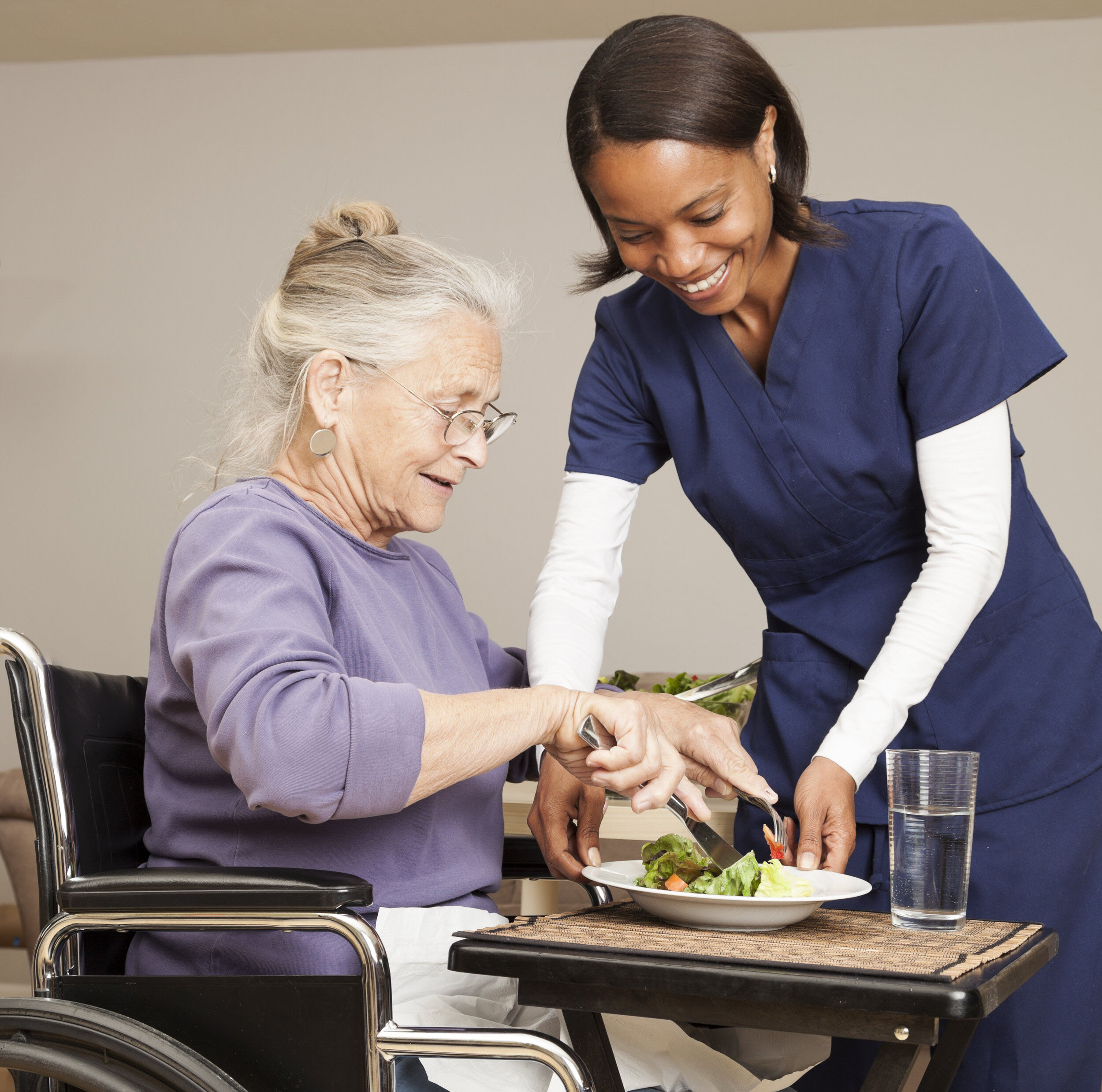 happy nurse serving food to elderly woman